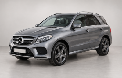 Серый Mercedes-Benz GLE на светлом фоне, вид спереди и сбоку.